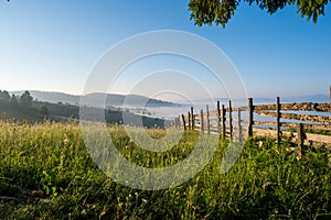 Mountain meadow in a sunrise enclosed by a wooden fence