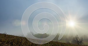 Mountain meadow timelapse at the autumn sunrise time. Wild nature and rural grass field. Morning heavy fog, sun rays and