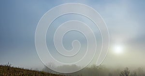 Mountain meadow timelapse at the autumn sunrise time. Wild nature and rural grass field. Morning heavy fog, sun rays and