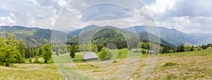 Mountain meadow with wooden herdsman huts in Carpathian Mountains, panorama
