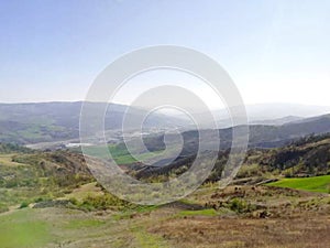 Mountain panorama in the early spring when nature awakens and where it is seen  green meadows and trees and in the distance in the photo