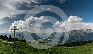 Mountain panorama with a gorgeous view of the Swiss Alps and Valleys and a summit cross