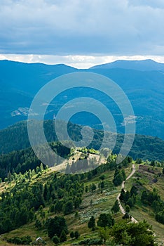 Mountain path going into the distance. Cell tower on the mountain. Green forest on the mountainside. Tourist trail