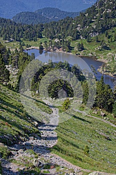 A mountain path leads to a lake and a forest