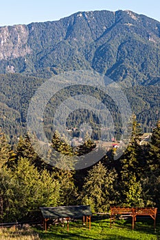 Mountain peak in bright sunlight. Wooden shelters in the foreground