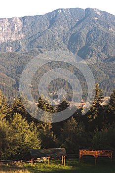 Mountain peak in bright sunlight. Wooden shelters in the foreground