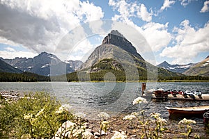 Mountain Peak Landscape Scene of Grinnell Point and Swiftcurrent Lake in Glacier National park. Boats docked in the water with a photo