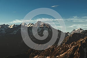 Mountain peak sunset landscape with gloomy dramatic mainly cloudy sky and orange and red sun beams