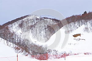 Mountain peak white snow with orange plastic fence in winter landscape in Japan.