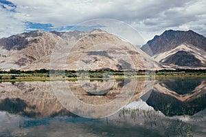 Mountain peaks reflect in water Nubra river