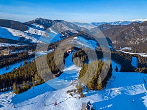 Horské štíty a lyžiarske svahy za slnečného počasia. Letecký pohľad