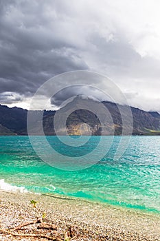 Mountain peaks up to clouds over turquoise water. Lake Wakatipu, New Zealand