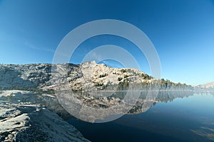 Mountain and pine trees reflecting on alpine lake