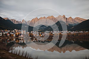 A mountain range with a lake in foreground and a town in the background