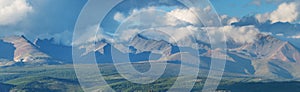 Mountain range, panoramic view. Peaks in the clouds, evening
