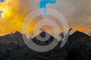 Mountain range snow peaks under orange sunset clouds