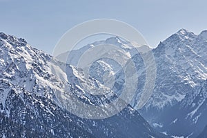 Mountain range, snowy peaks, border between forest highlands. Karakol gorge landscape. Winter in Kyrgyzstan mountains