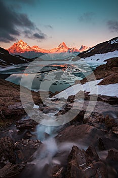 Mountain range at sunset. flowing water. mountains and snow