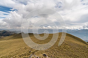 a mountain range with yellow grass and cloudy sky