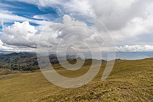 a mountain range with yellow grass and cloudy sky