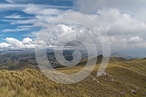 a mountain range with yellow grass and cloudy sky