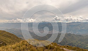 a mountain range with yellow grass and cloudy sky