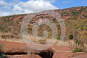 MOUNTAIN WITH RED ROCK FORMATION CLIFFS AND CONGLOMERATE BOULDERS IN THE FOREGROUND IN A SOUTH AFRICAN LANDSCAPE