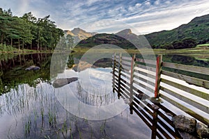 Mountain reflections in lake with fence.