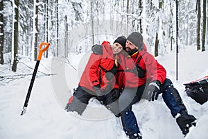 Mountain rescue service on operation outdoors in winter in forest, digging snow with shovels.