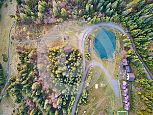 Mountain resort, village and hotel with pond and forest. Aerial top view on lake, rural dirt road in woods, ski lift. Travel photo