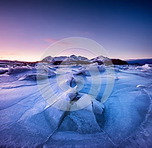 Mountain ridge and reflection on the frozen lake surface. Natural landscape on the Lofoten islands, Norway.