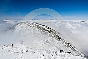 Mountain ridge and sea of clouds; the tops of Mount San Gorgonio and Mount San Jacinto in the background; hiker coming up a steep