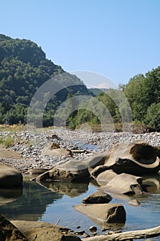 Mountain river in Adygea, rocky beach, large boulders, summer day in the mountains,
