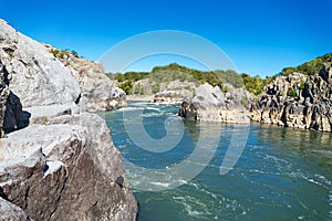 Mountain river flowing among the harsh sheer stones in the mountains. Sunny day, blue sky
