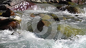 Mountain river flowing over stones in slow motion