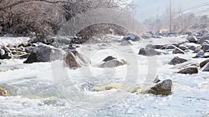 mountain river flowing between rocky shores. Winter mountain river in wood, water and stones, slow motion, landscape