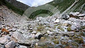 The mountain river flows from the mountains through large stones