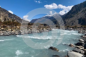 The mountain river flows under the blue sky on the distant horizon