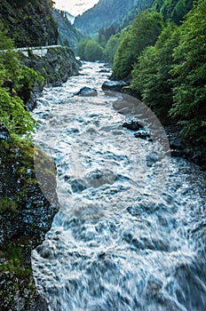 A mountain river flows between the woods of rocks.