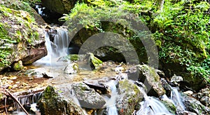 Horská řeka se zelenými mechem obrostlými kameny a malým vodopádem. Zachyceno v Prosieckej Dolině, Slovenský přírodní park na Slovensku..