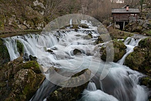 Mountain river with mossy rocks and wooden watermills