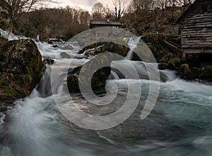 Mountain river with mossy rocks and wooden watermills
