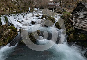 Mountain river with mossy rocks and wooden watermills