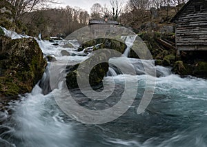 Mountain river with mossy rocks and wooden watermills