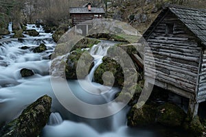 Mountain river with mossy rocks and wooden watermills