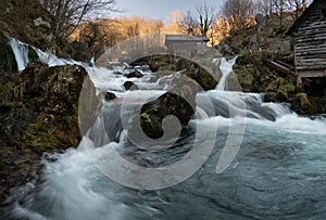 Mountain river with mossy rocks and wooden watermills