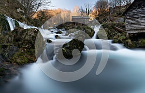 Mountain river with mossy rocks and wooden watermills