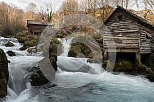 Mountain river with mossy rocks and wooden watermills