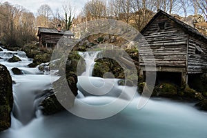 Mountain river with mossy rocks and wooden watermills in long exposure