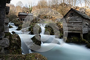 Mountain river with mossy rocks and wooden watermills in long exposure